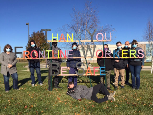 WHSS staff and students pictured next to a wooden sign the made to thank frontline workers.