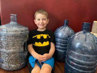 Jake, a student at Elora Public School, sits with his collection of pop tabs. June 2021.