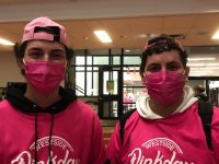 This photo shows two young boys wearing pink hats, pink masks and pink shirts.