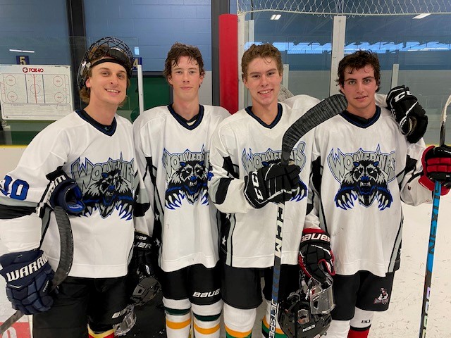 This photo features a close up shot of 4 hockey players on the ice in a hockey rink.