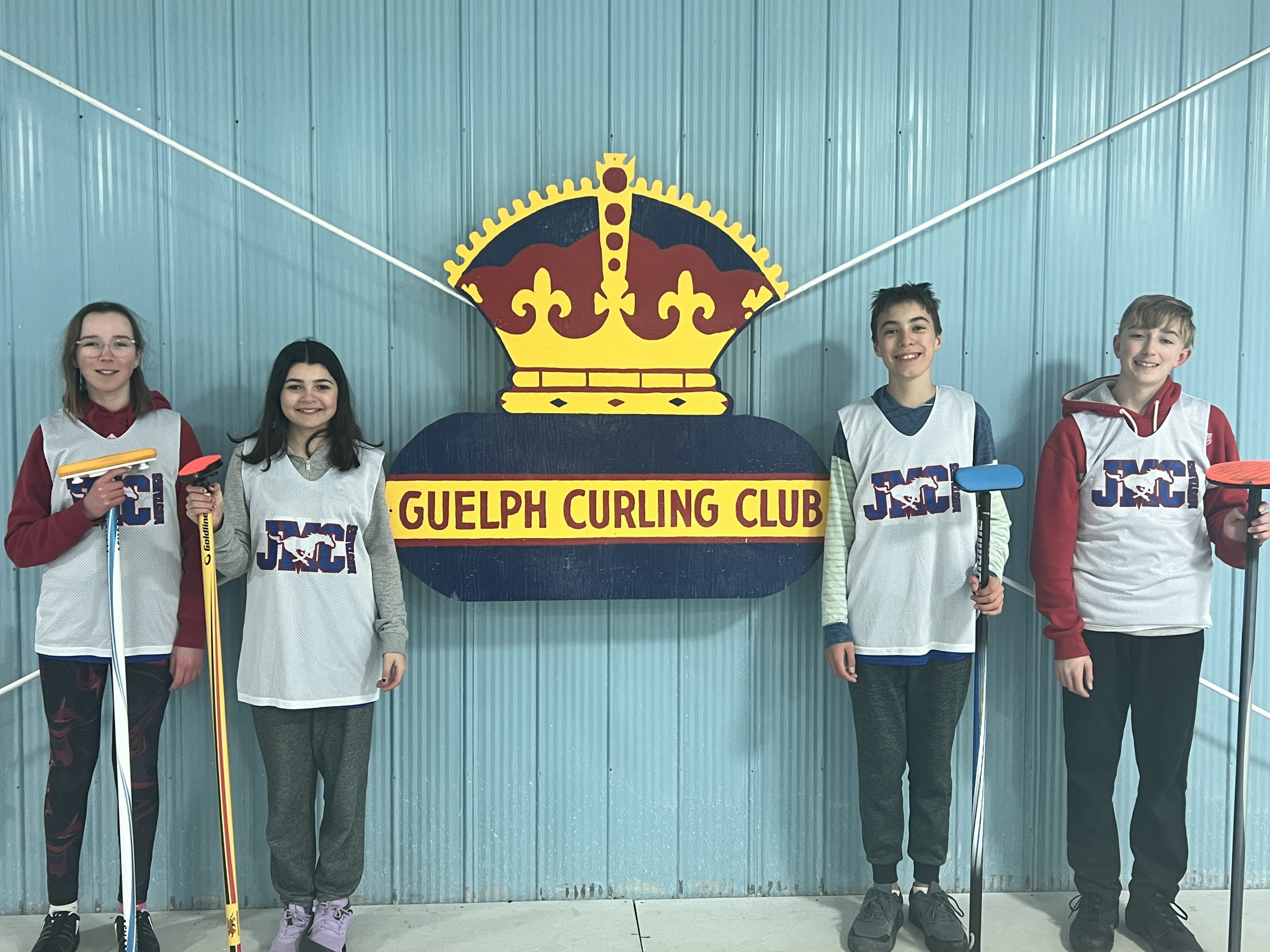 This photo features 2 girls and 2 boys with curling stick outside the Guelph Curling Club.
