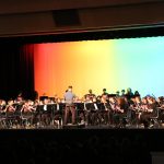 This photo features a band performing with a gradient rainbow background.