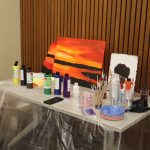 This photo features canvas paintings of a sunset on a table with other art supplies.
