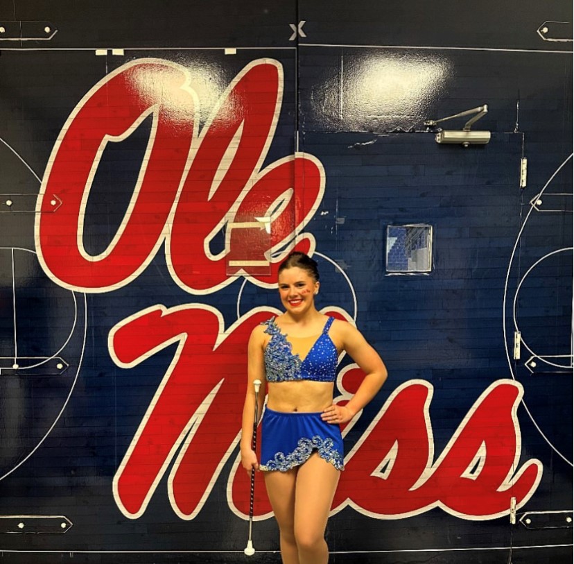 This photo features Elsie P. posing in front of an Ole Miss banner.
