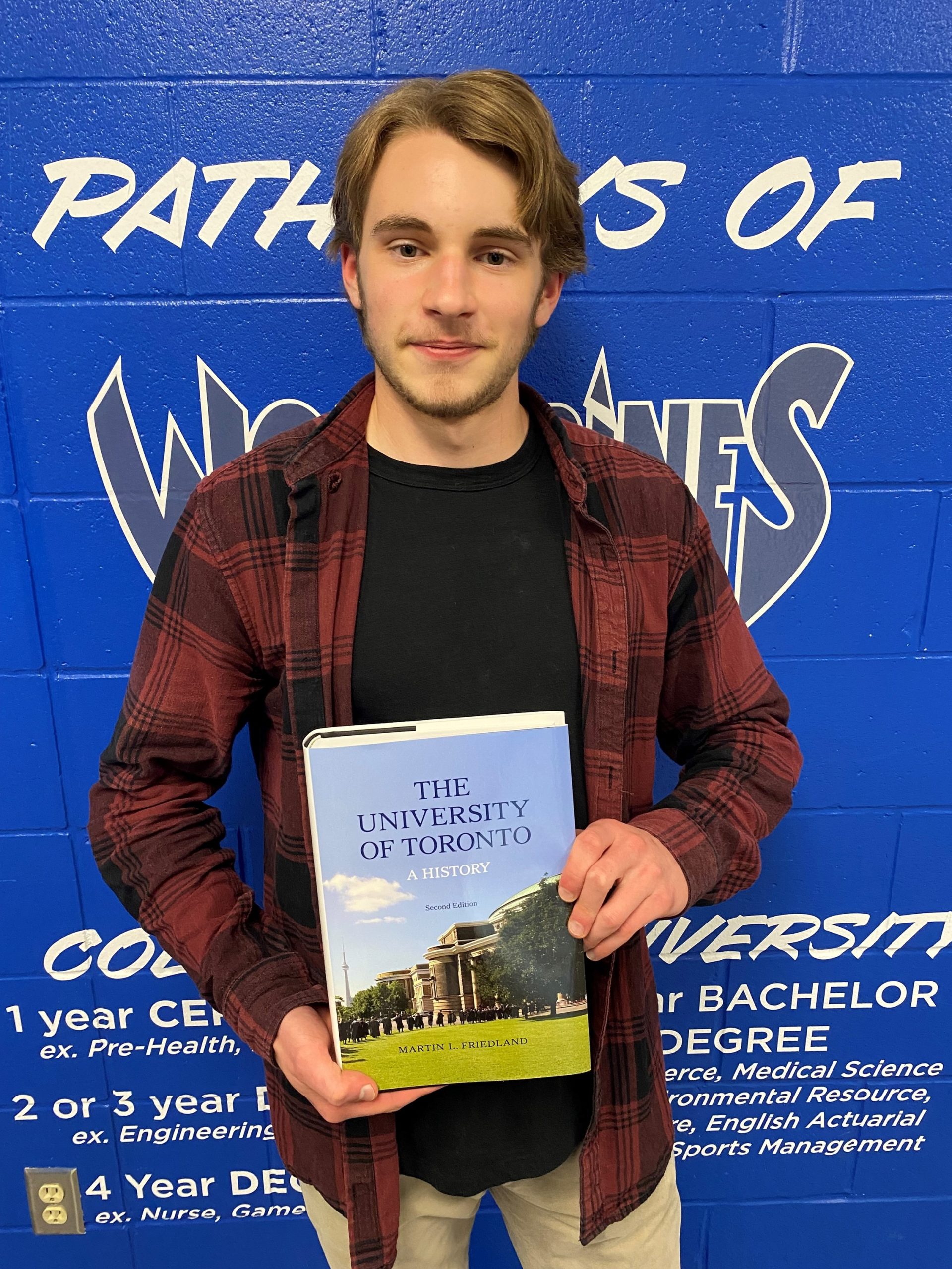 This photo features Joey T. holding a book on the history of The University of Toronto. 