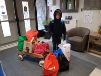 This photo features Hudson G. with a wagon full of food drive donations.
