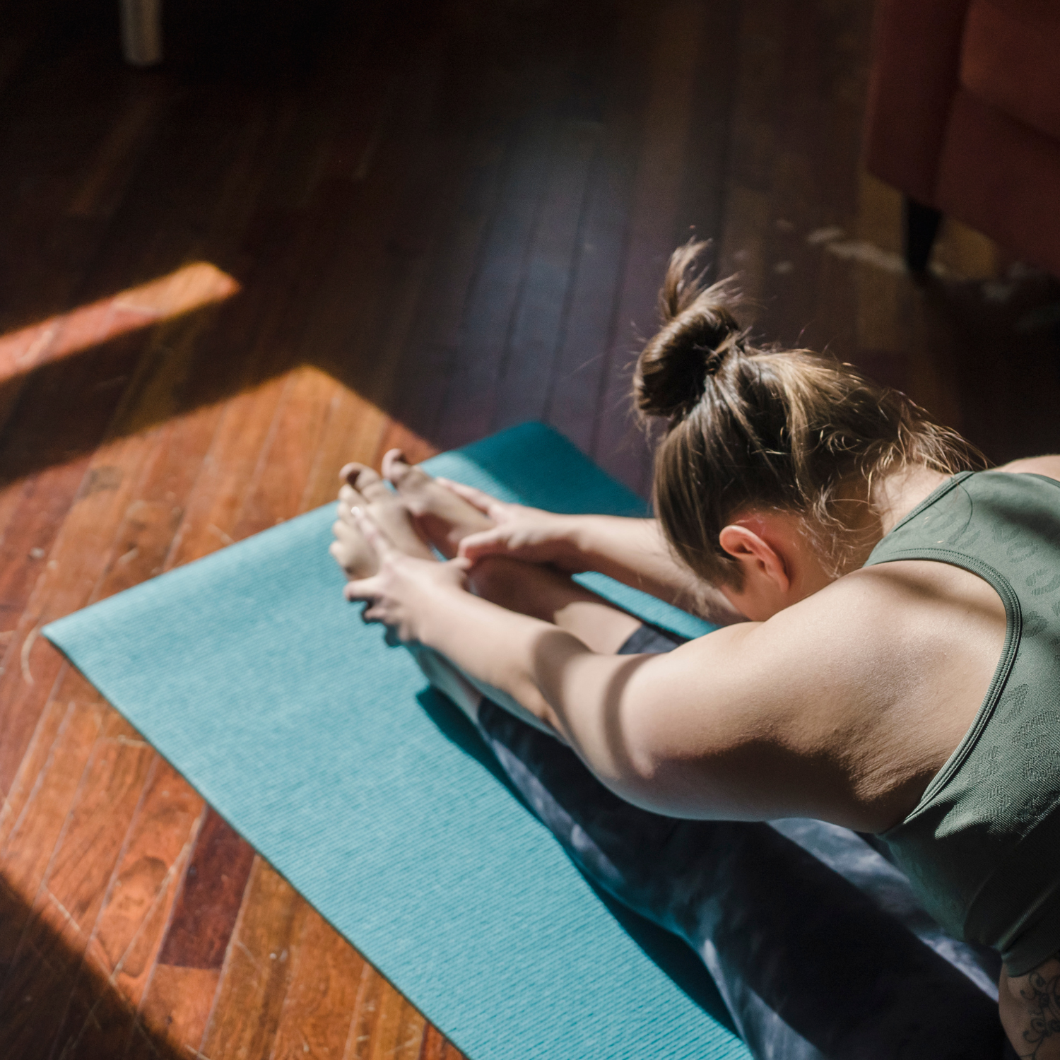 A picture of a person sitting on a yoga mat, stretching
